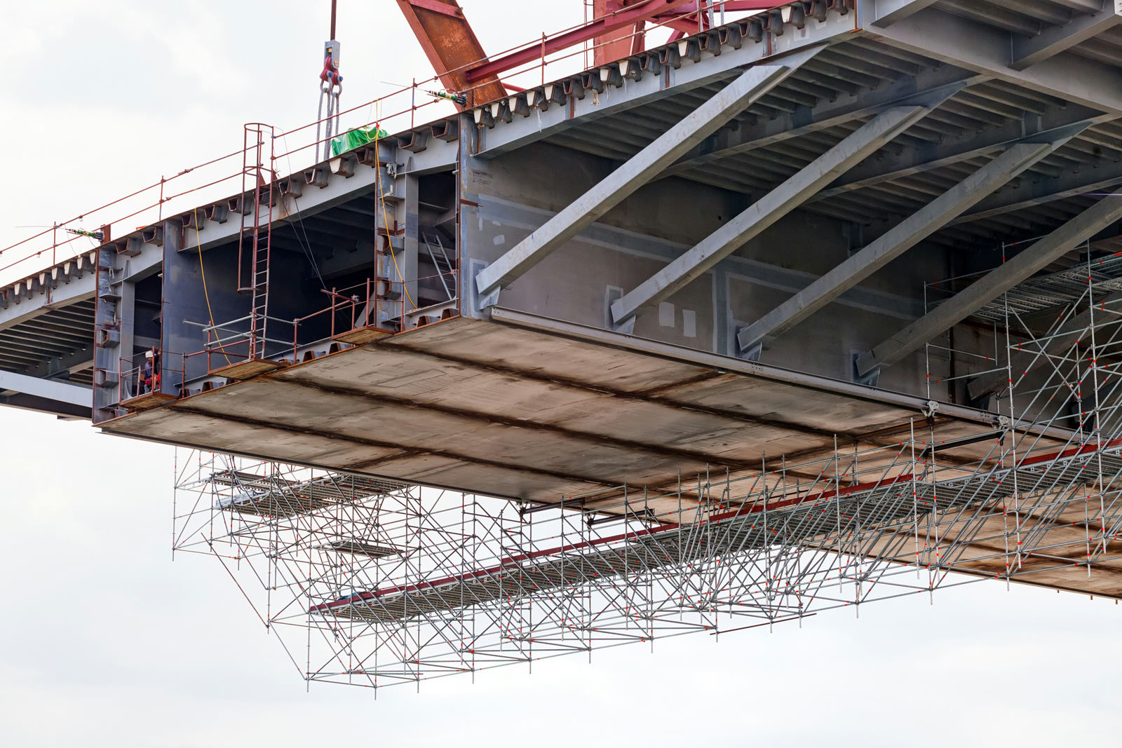 Steel bridge construction and extensive scaffolding are viewed from below.